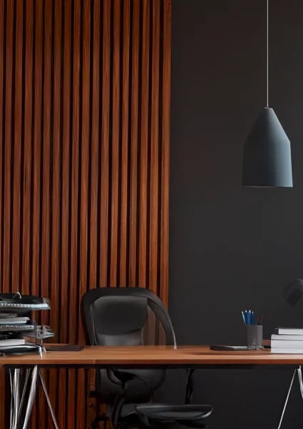Modern office desk with black chair, wooden desk against red corrugated wall, black pendant lamp hanging above, dark wall background