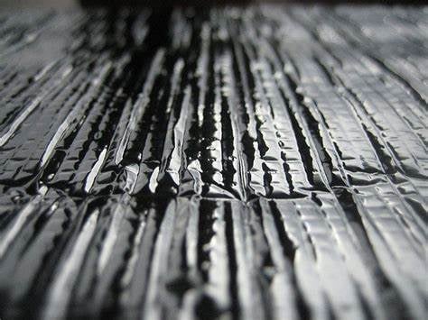 Close-up of weathered wood surface with deep linear grain patterns and texture in black and white