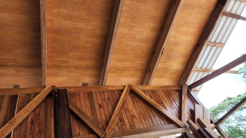 Interior view of wooden beam ceiling and triangular roof trusses with skylights in modern construction
