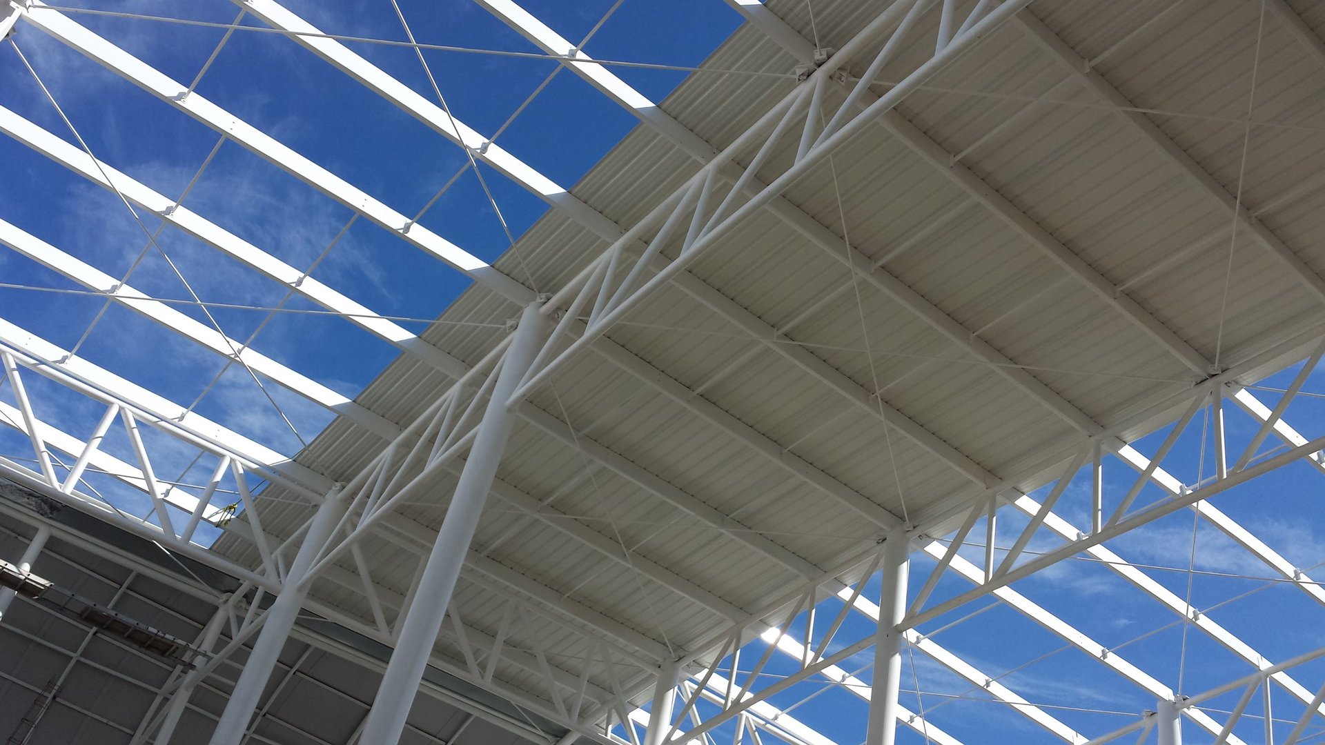Structural metal framework and beams of a building under construction against a blue sky