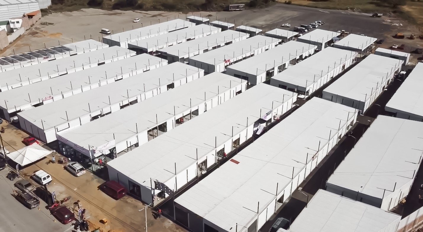 Vista aérea de una gran obra industrial con naves de techos blancos en desarrollo